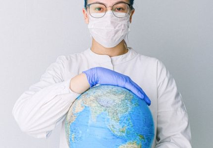 person with a face mask and latex gloves holding a globe