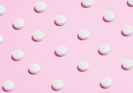 white round capsule on pink background close up photography